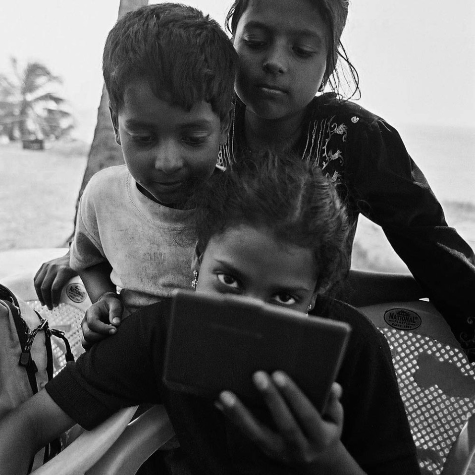 Three young Indians looking into an electronic device, Varkala.